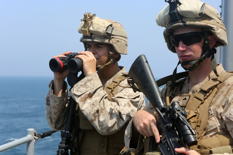 two marine personnel take pictures on a ship