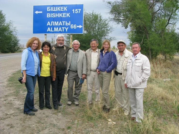 some people and two men standing near the highway sign