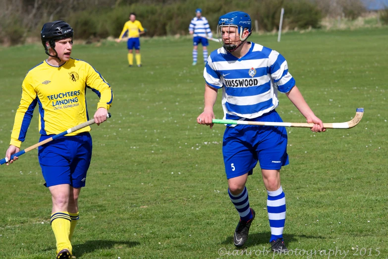 one boy in blue and yellow is holding a stick