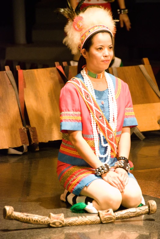 a woman sitting on the floor wearing an indian head dress