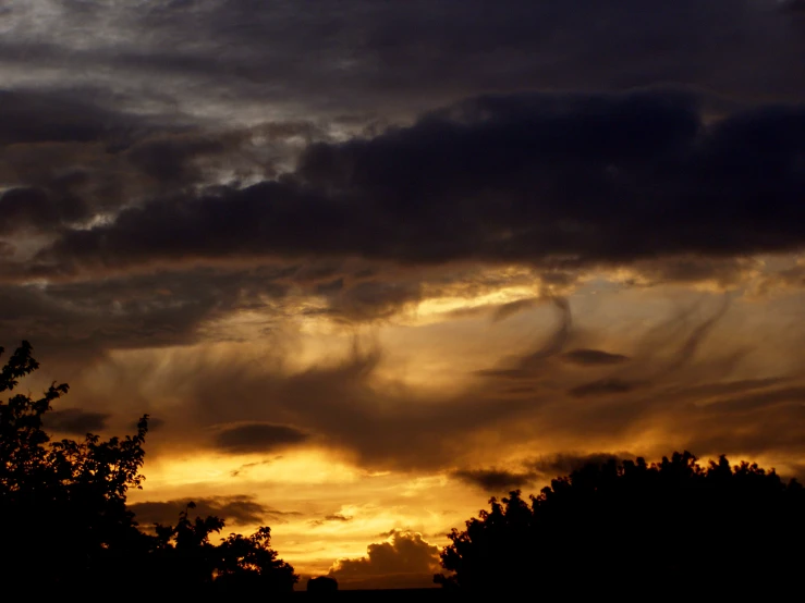 some clouds and a clock tower with trees