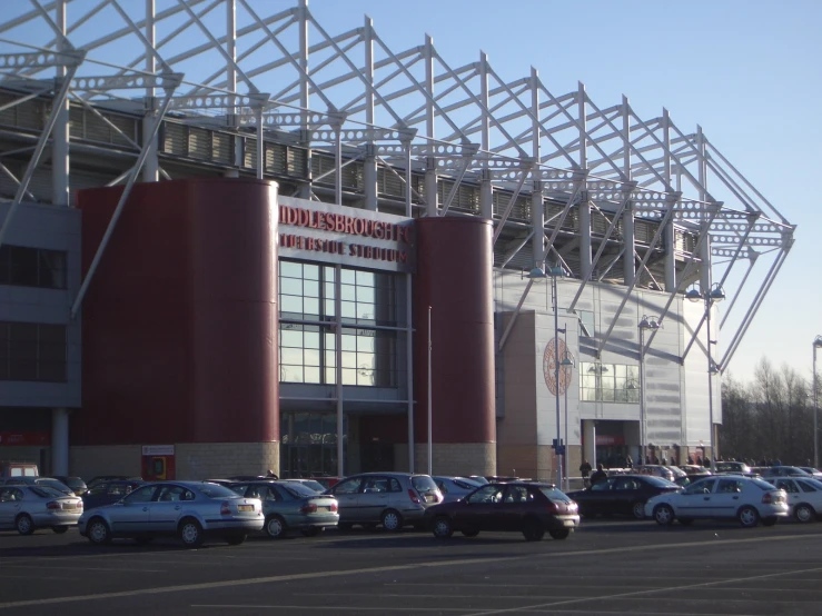 the front of a stadium with many cars parked
