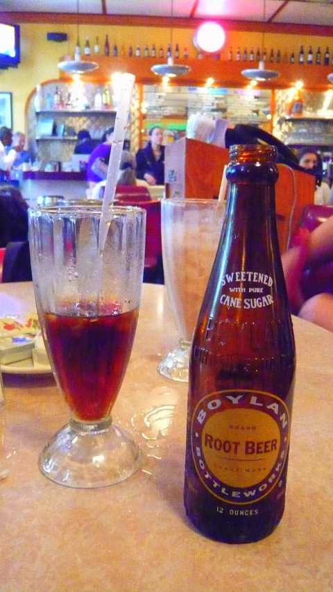 the bottle of beer is on the table next to some glasses