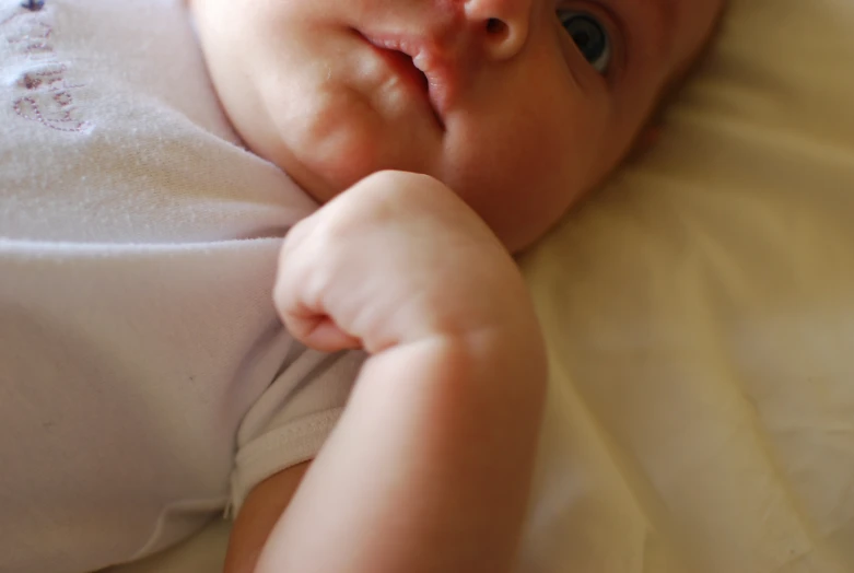 a close up of a baby on a bed with an eye