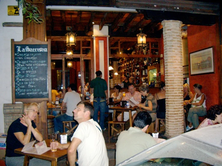 many people at tables in a restaurant near some food