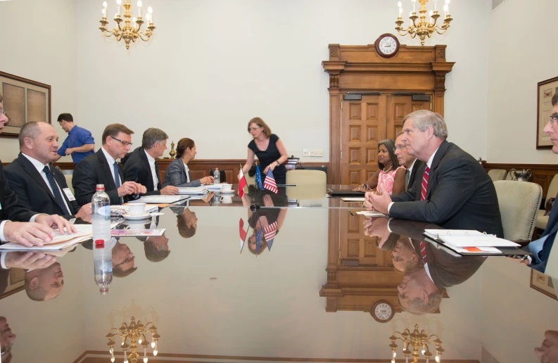 a room filled with people seated at a table talking