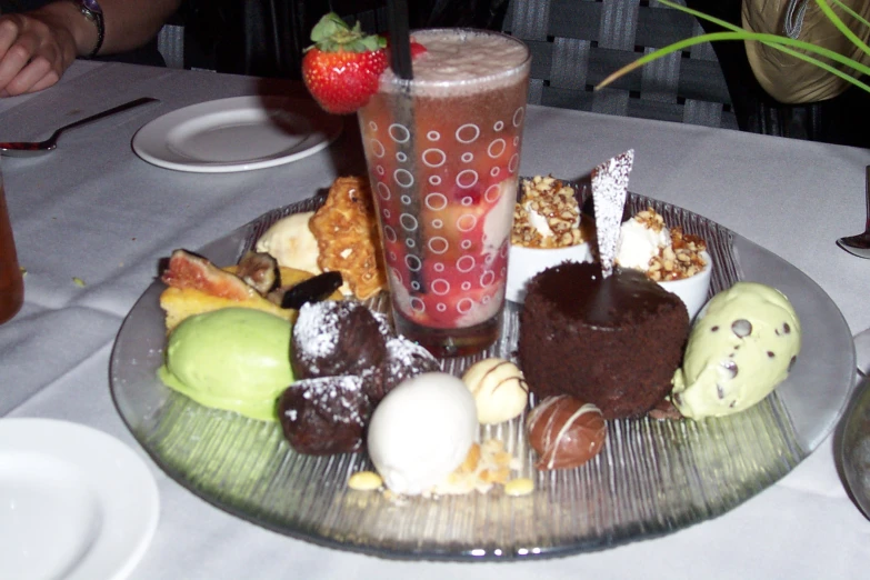 a plate with various sweets on it and a cup of fruit