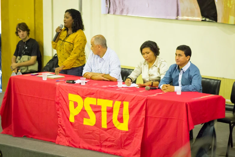 four people are sitting at a table signing papers