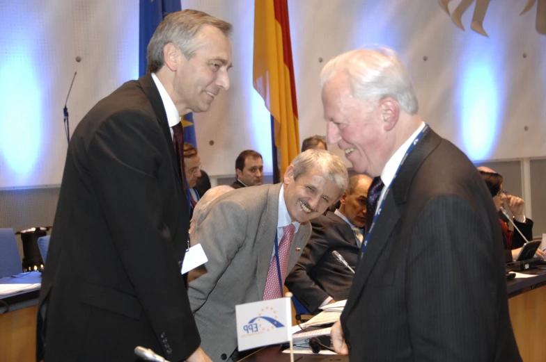 two men shaking hands while people stand and sit at tables