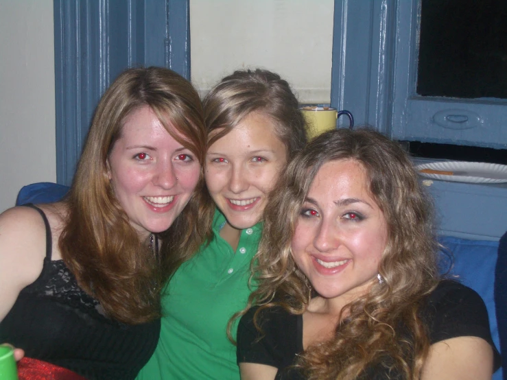 three girls are sitting together smiling for the camera