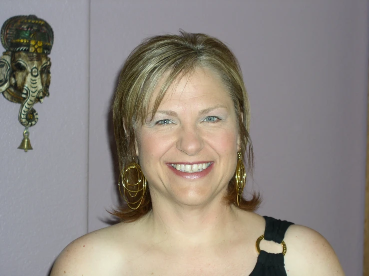a woman with large golden earrings and a black top smiling