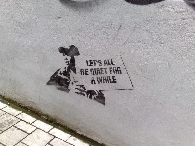 there is a sign on the side of a building that says let's all be quiet for a while