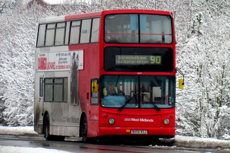 a red double decker bus is driving down the road