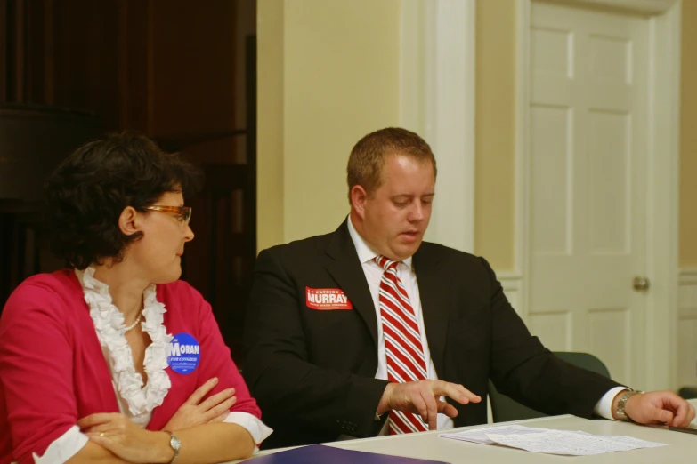 a man and woman sitting at a desk discussing soing