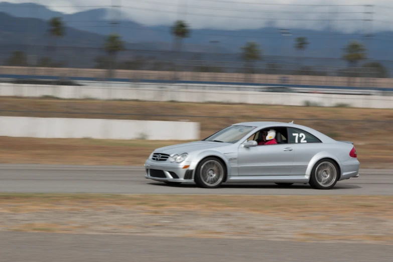 a silver car speeding on a race track