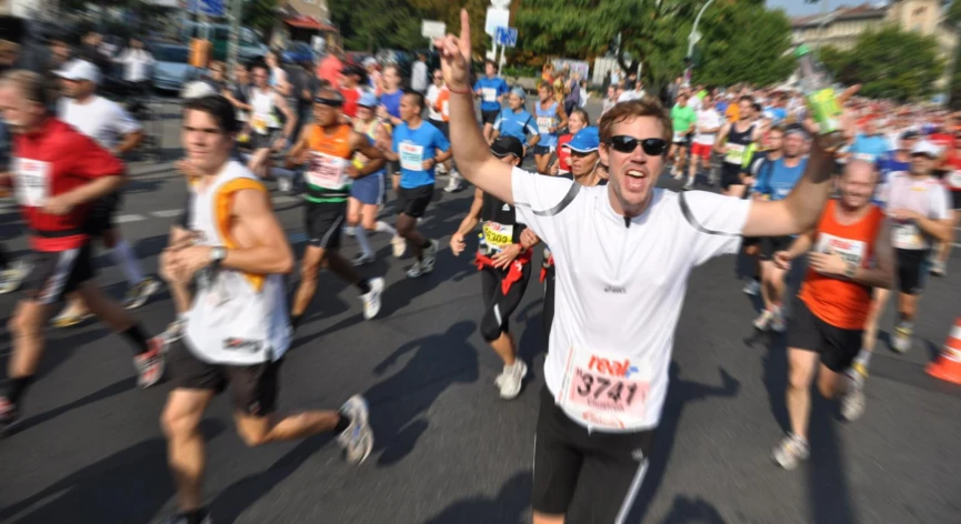 a man with his arm up as he crosses a marathon course