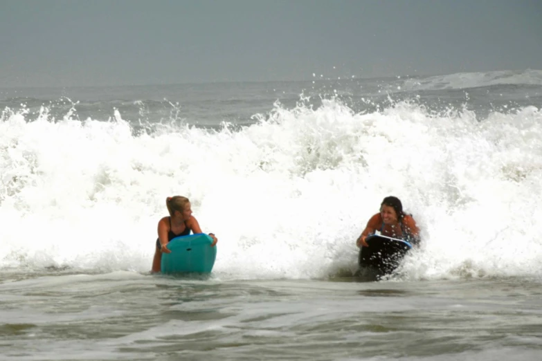 two children on boogie boards ride waves in the ocean