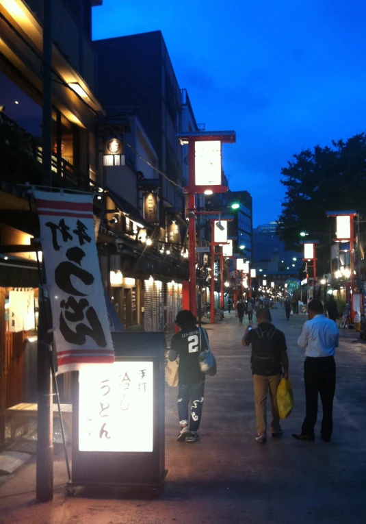 a crowded street at night with shop lights and signs