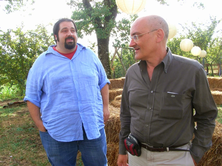 two men are standing near hay bales talking