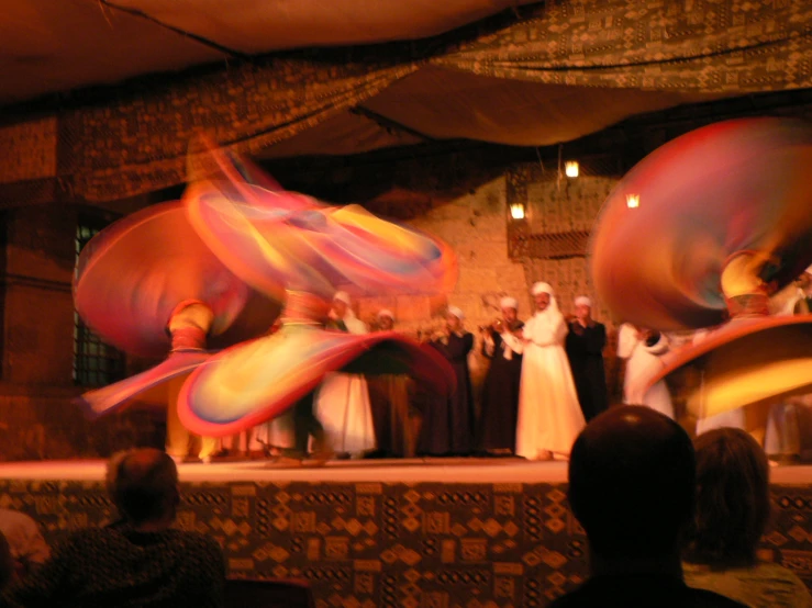 performers perform on stage while a crowd looks on