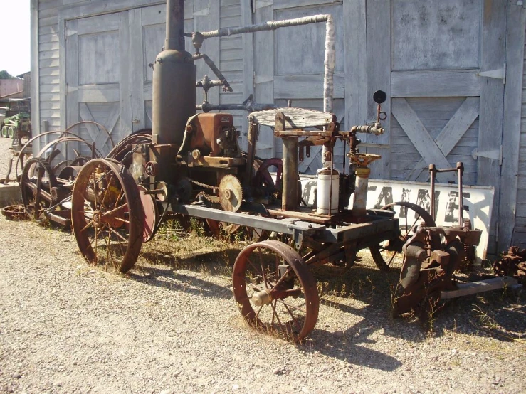 a small engine and two old machinery sitting in front of a gray building