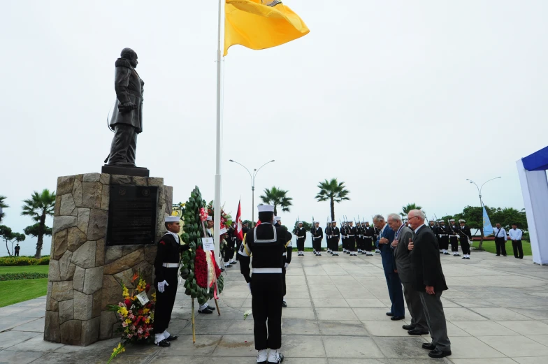 people in uniform stand outside the flag of some sort