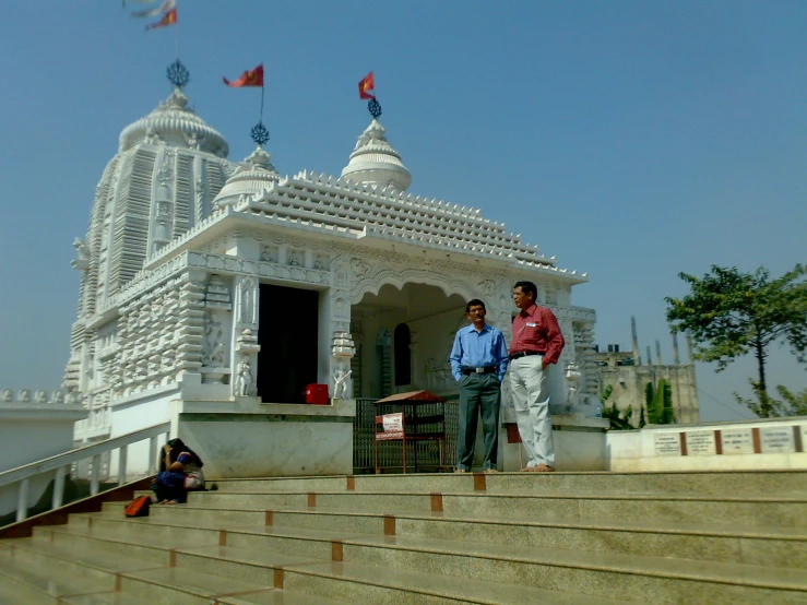 two men standing in front of a white building