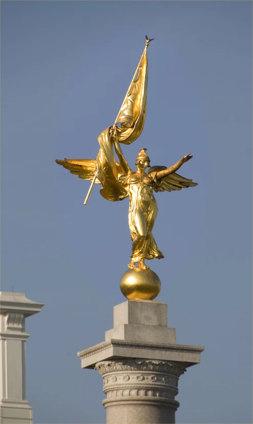a gold statue is atop of a white column