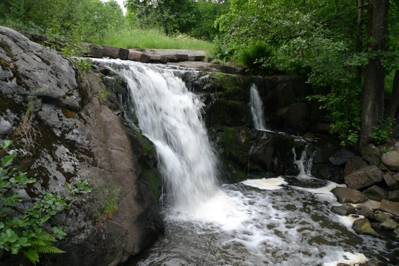 water rushing over some rocks into the middle of a stream