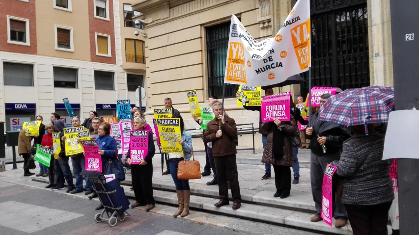 large crowd standing on stairs holding posters and umbrellas