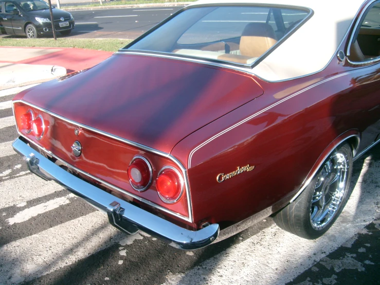 a maroon and white car is parked by a curb