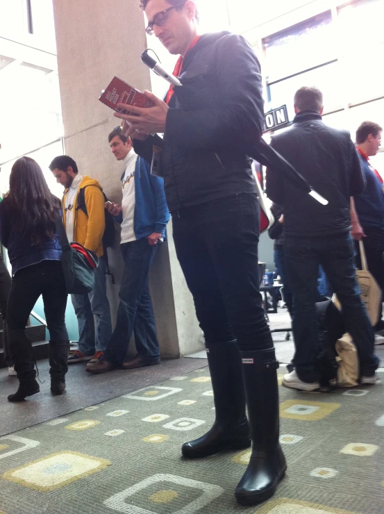 some people stand in line with one holding an electronic device