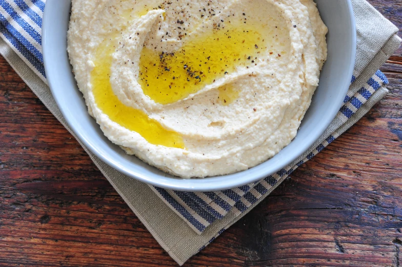 a bowl filled with hummus and an oil drop