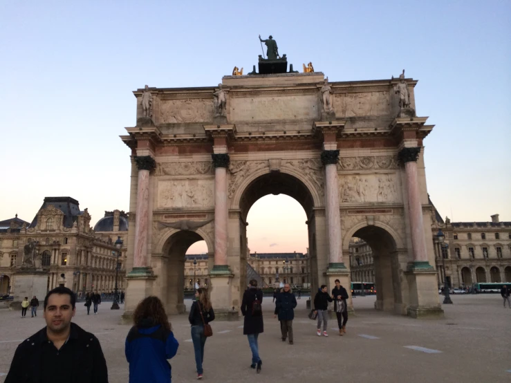 people are walking near a large gate in the sun