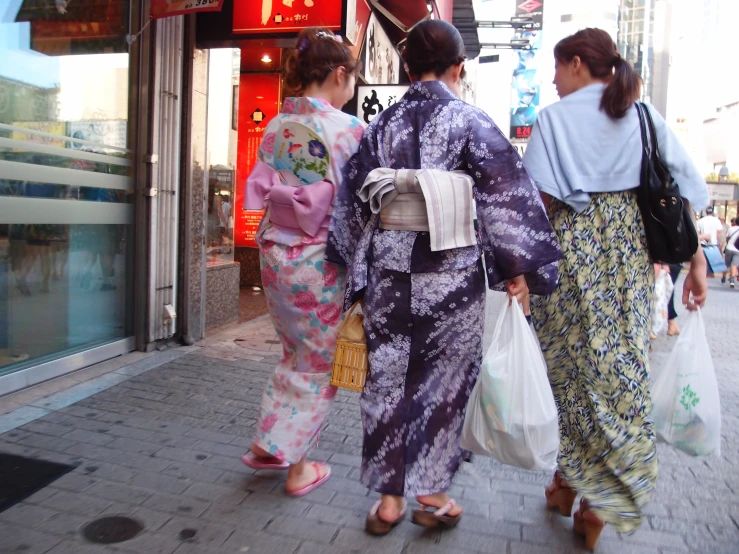 three women walking down a street with shopping bags