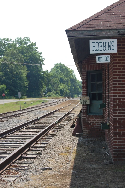 the small red brick depot is next to the train tracks