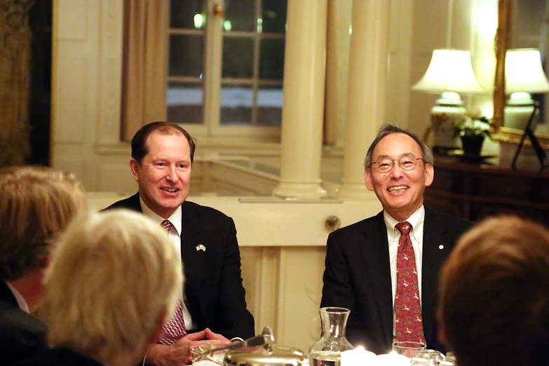 two men sit next to each other at a dinner table