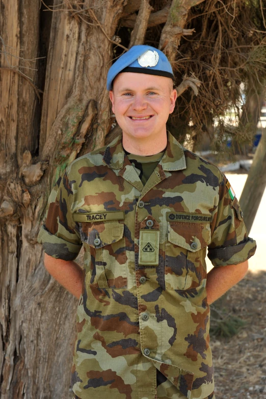 a young man wearing a camouflage uniform is smiling