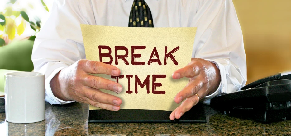 a man holding up a note with the word break time written in it