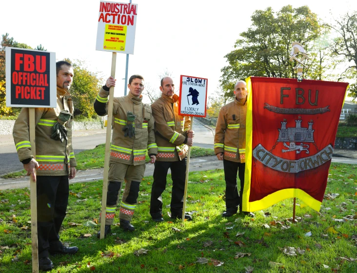 some fire fighters are holding up signs and a fire department flag