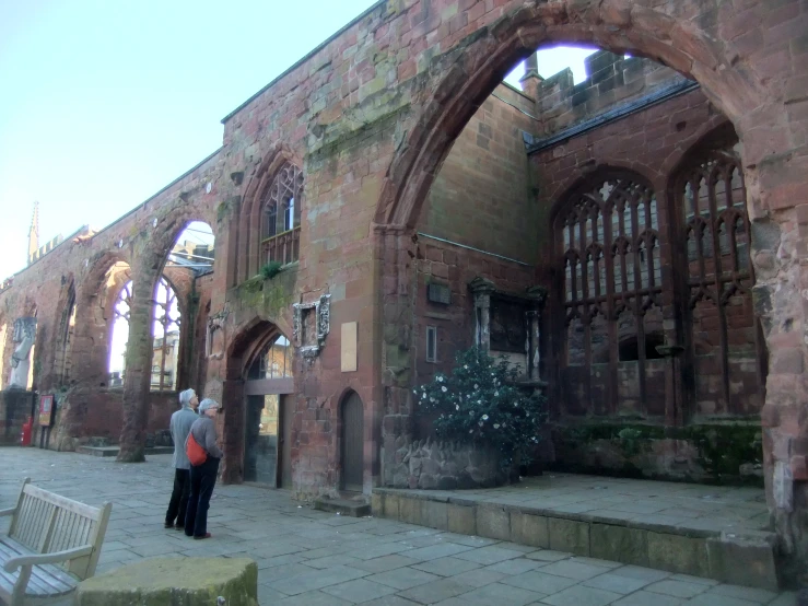 two people stand by an old brick building