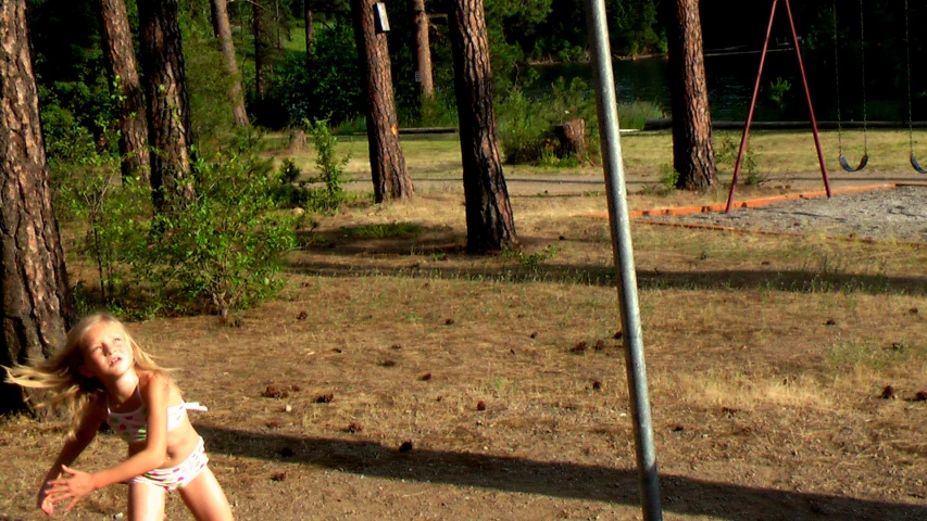 a little girl standing on top of a field holding a tennis racket