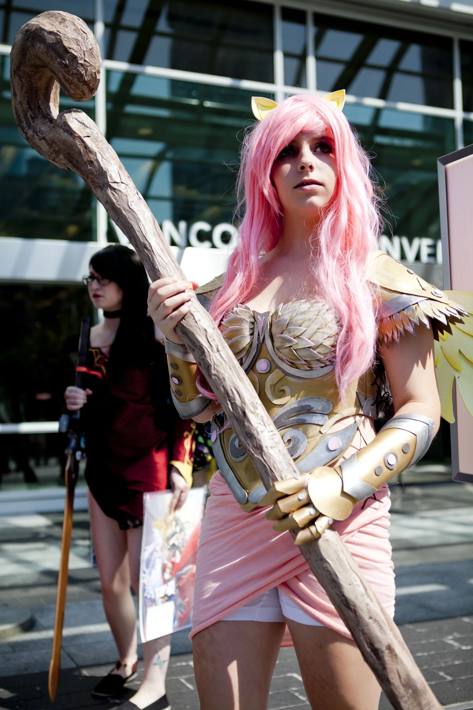 a pink haired woman wearing armor with a big wooden stick and wearing costume