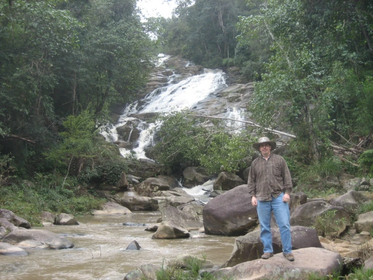 a person standing on some rocks near a stream