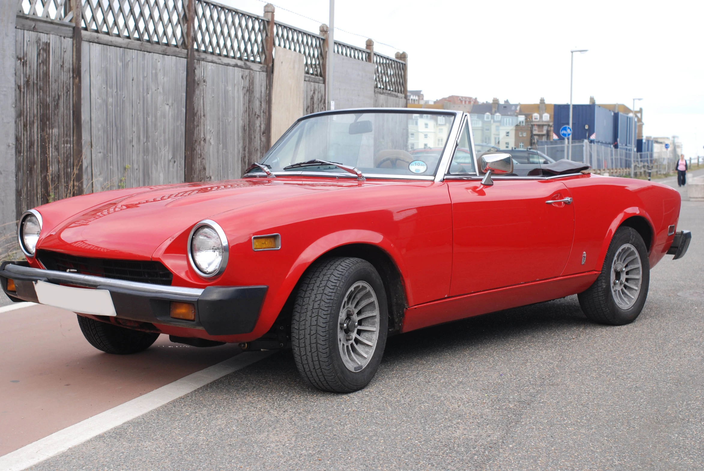 a red sports car parked beside a wooden gate