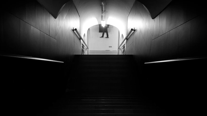 a black and white image of a person walking down stairs