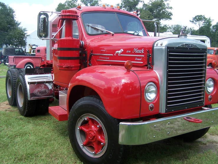 a bright red truck sits in a grassy area