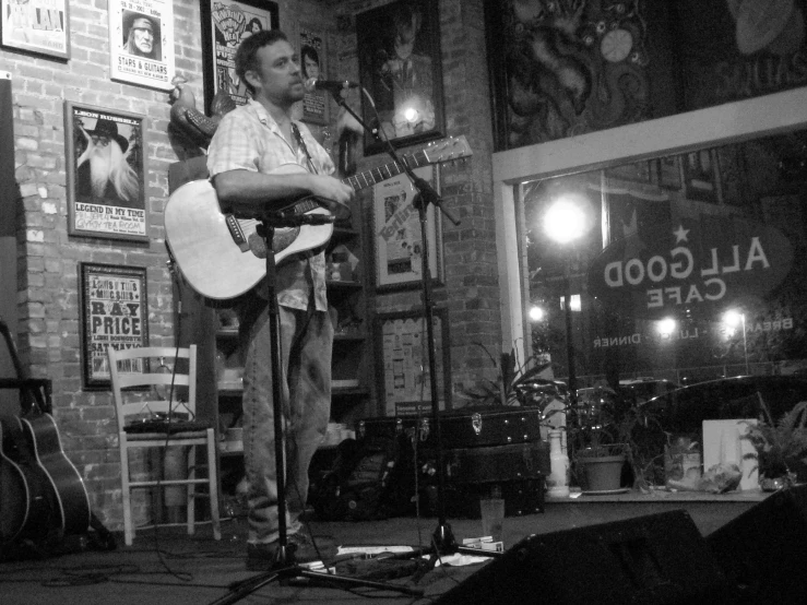 a man standing in front of a microphone while holding a guitar