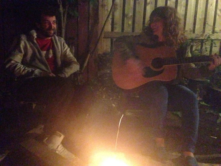 a man is playing a guitar while sitting on a bench outside