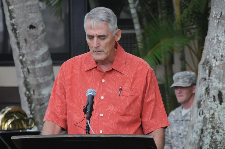 the man in the red shirt is giving a speech